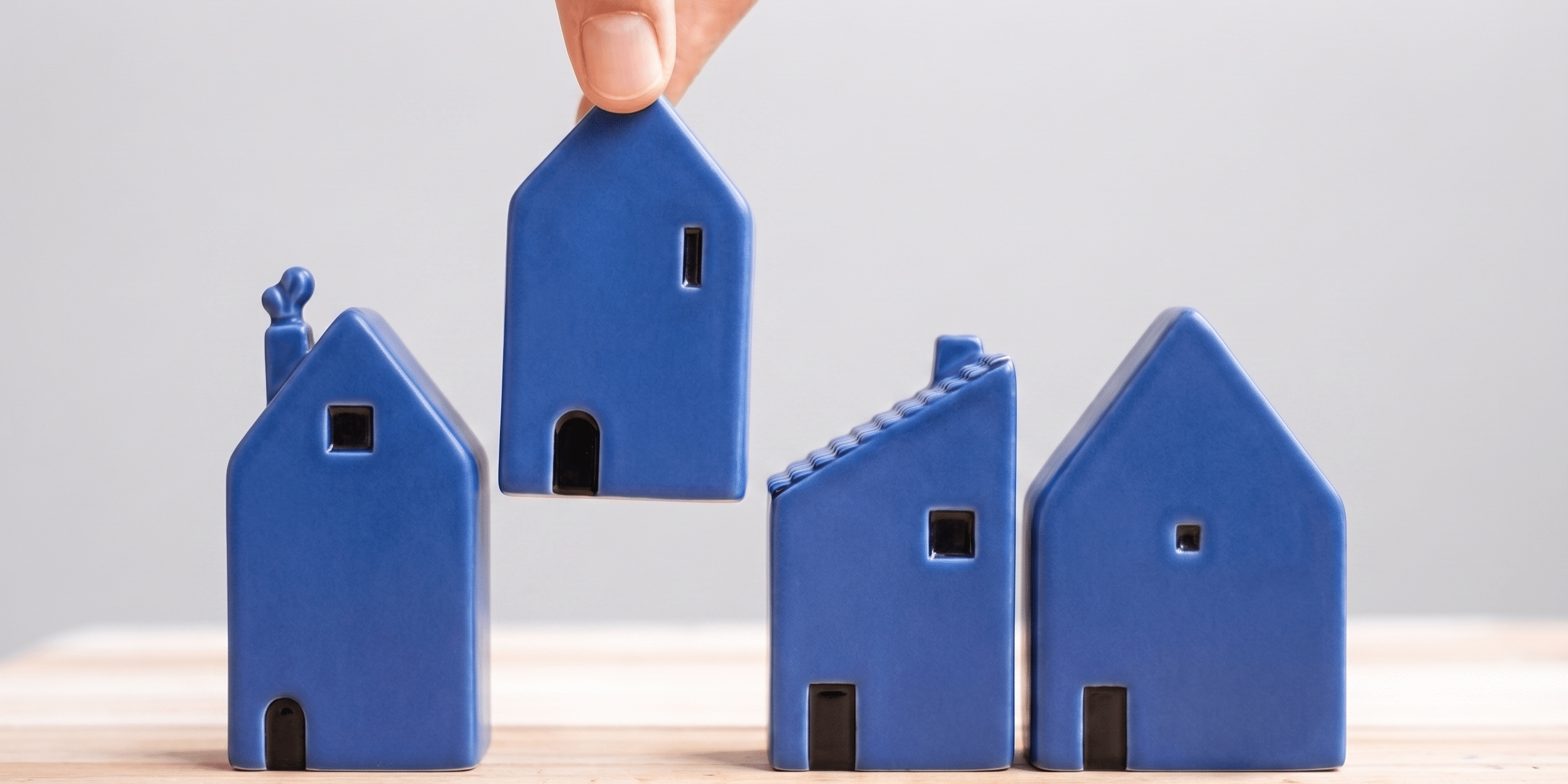 Cuatro casitas de cerámica minimalistas azul cobalto sobre mesa de madera.